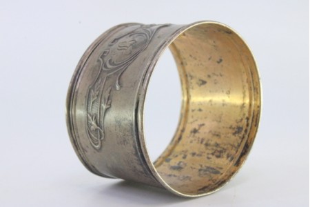 Argola de guardanapo em prata com motivos florais relevados envolvendo cartela para monograma.